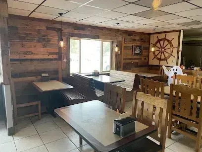 Mobile Detailing-Interior of a restaurant with wood paneling, booths, tables, and a large ship wheel decoration.