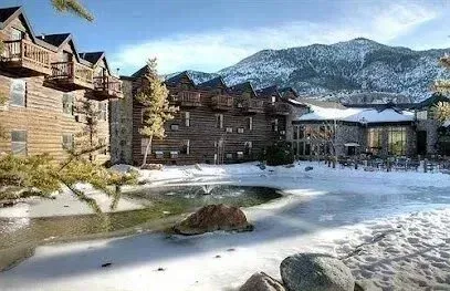 Mobile Detailing-Snowy lodge with log cabins, a frozen pond, and a mountain backdrop.