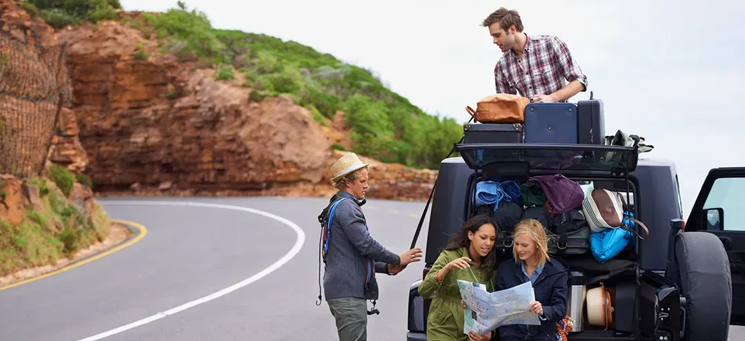 A group of people are standing next to a jeep on the side of the road.