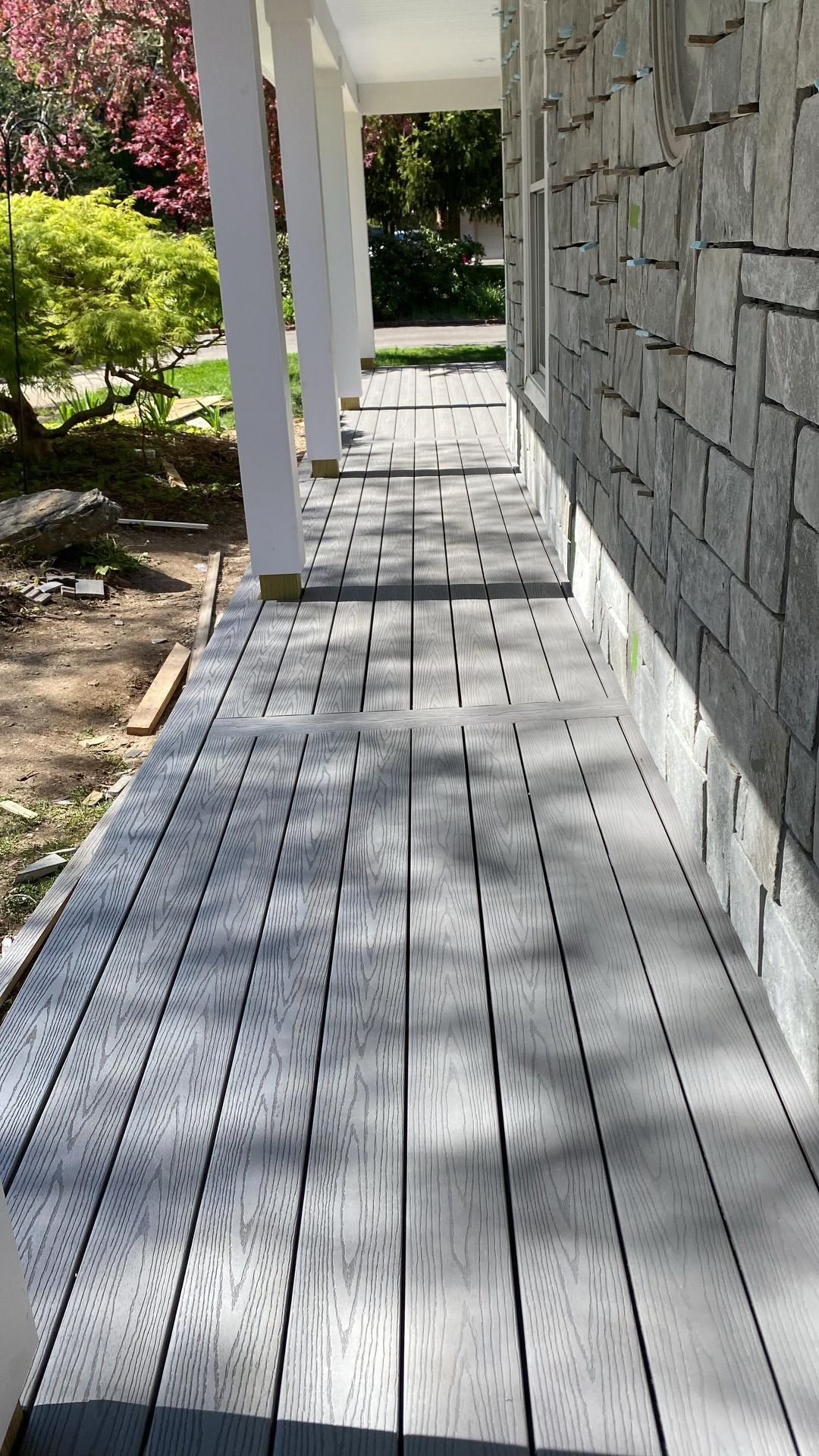 A wooden walkway leading to a house with a stone wall.