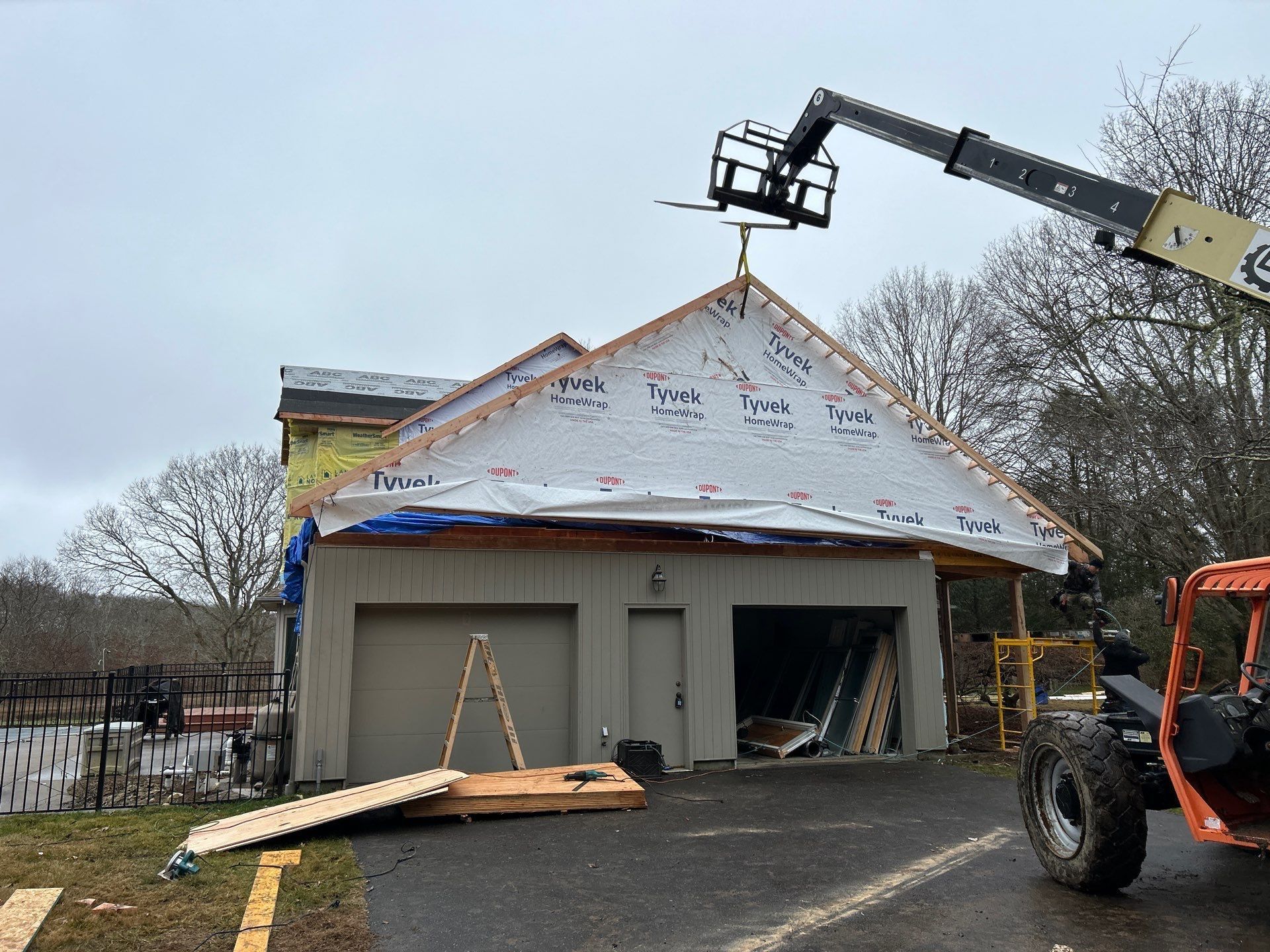 A crane is lifting a roof over a garage.