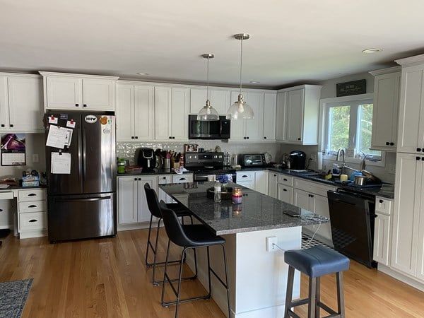 A kitchen with white cabinets , stainless steel appliances , and a large island.