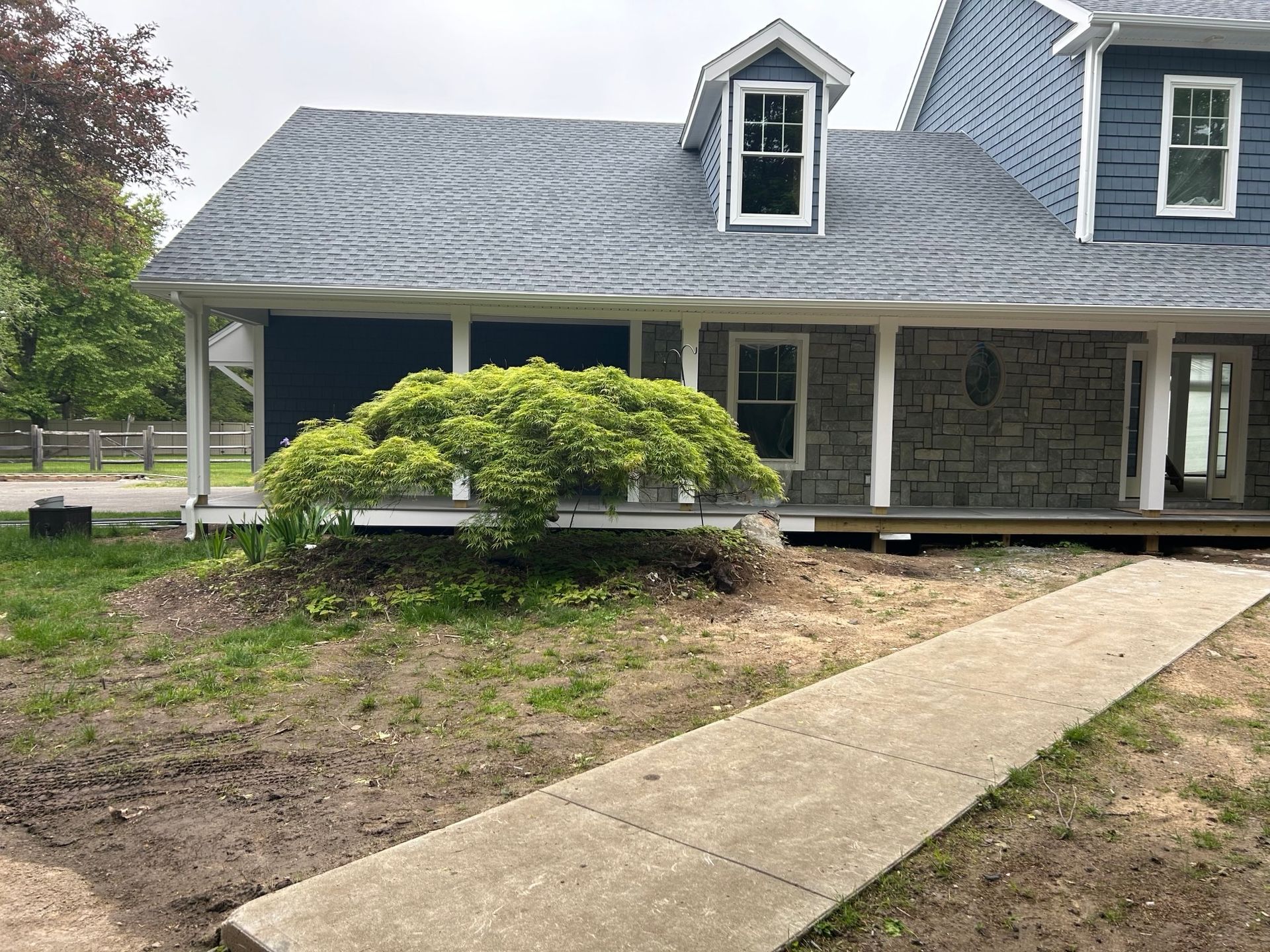 A blue house with a porch and a walkway leading to it.