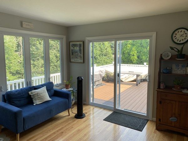 A living room with a blue couch and a sliding glass door leading to a deck.