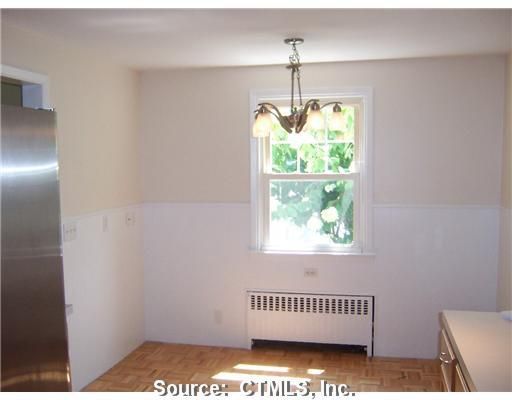 An empty kitchen with a stainless steel refrigerator and a window