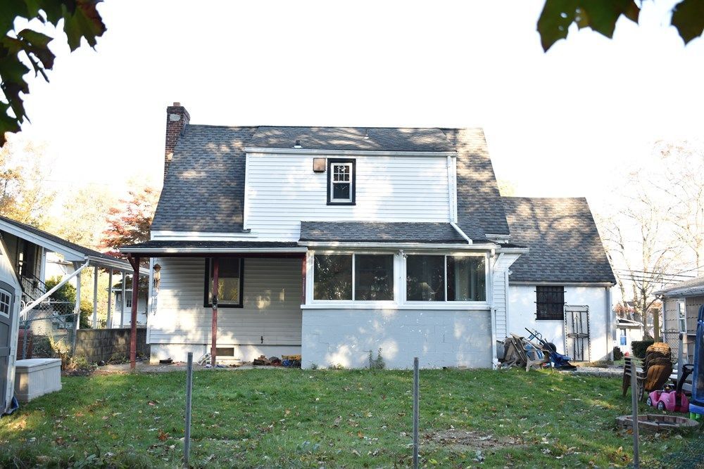 A white house with a black roof is sitting on top of a lush green field.