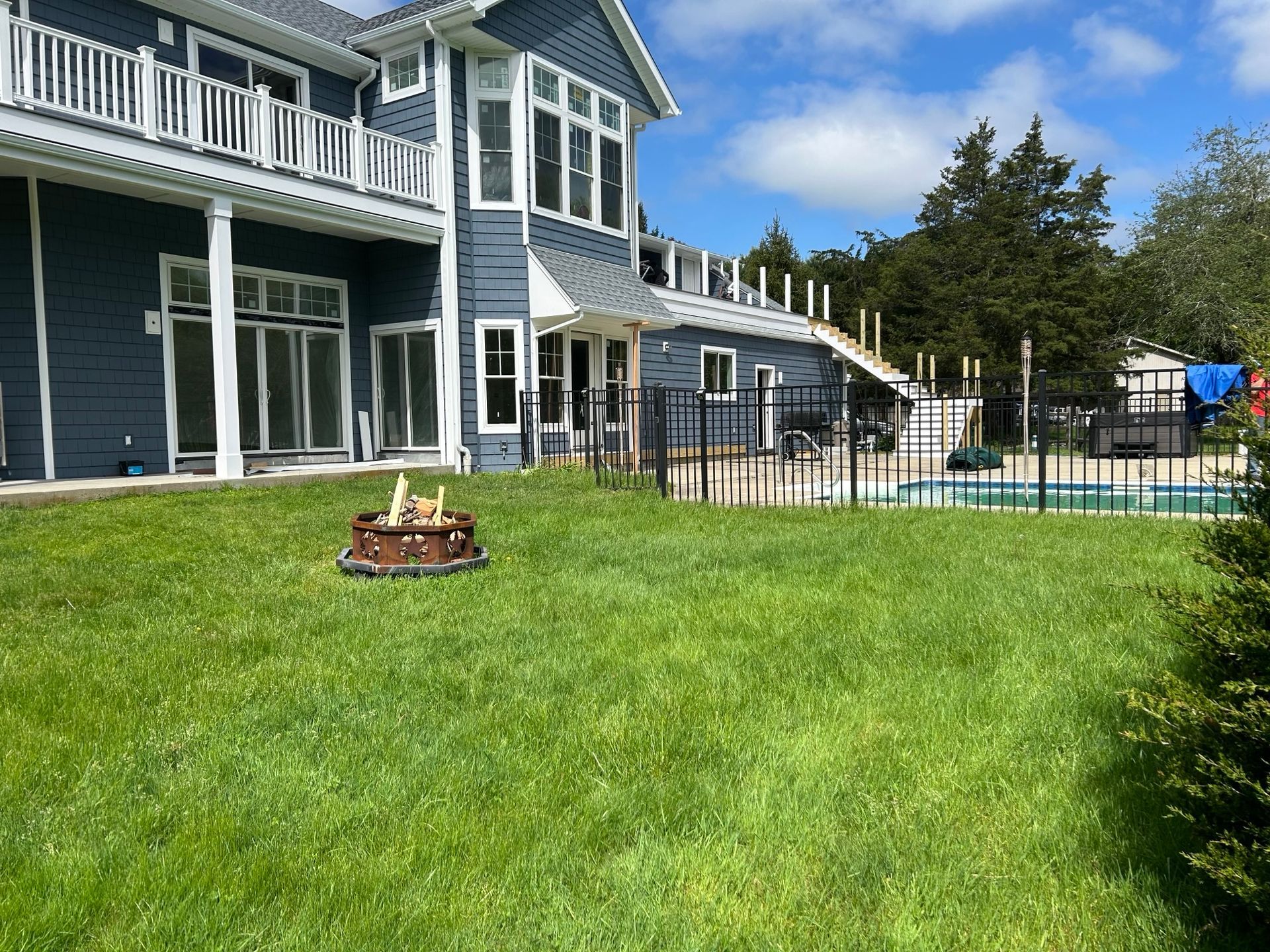 A large house with a swimming pool and a fire pit in front of it.