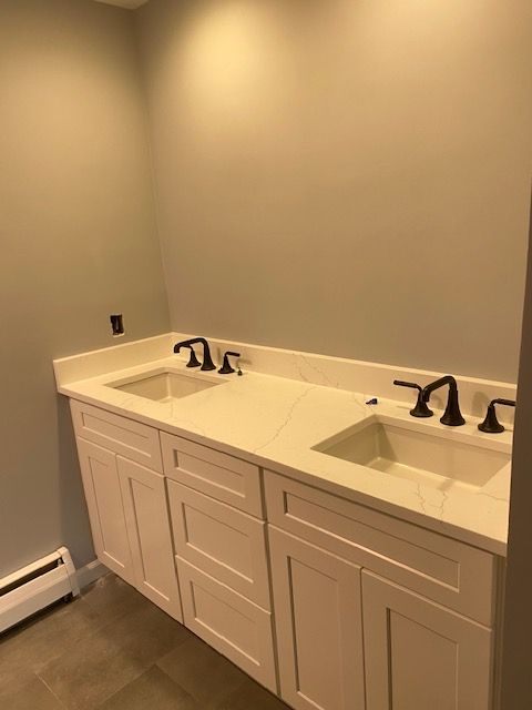 A bathroom with two sinks and white cabinets.