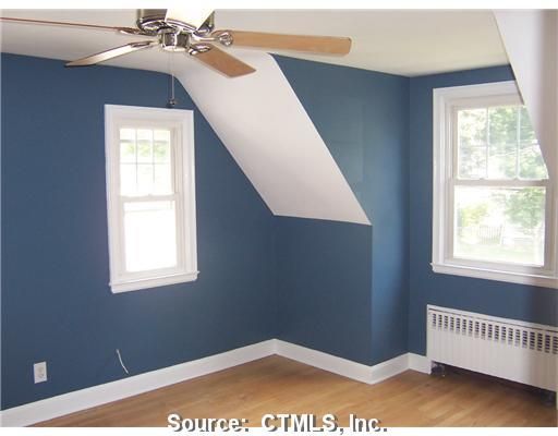 An empty room with blue walls and a ceiling fan