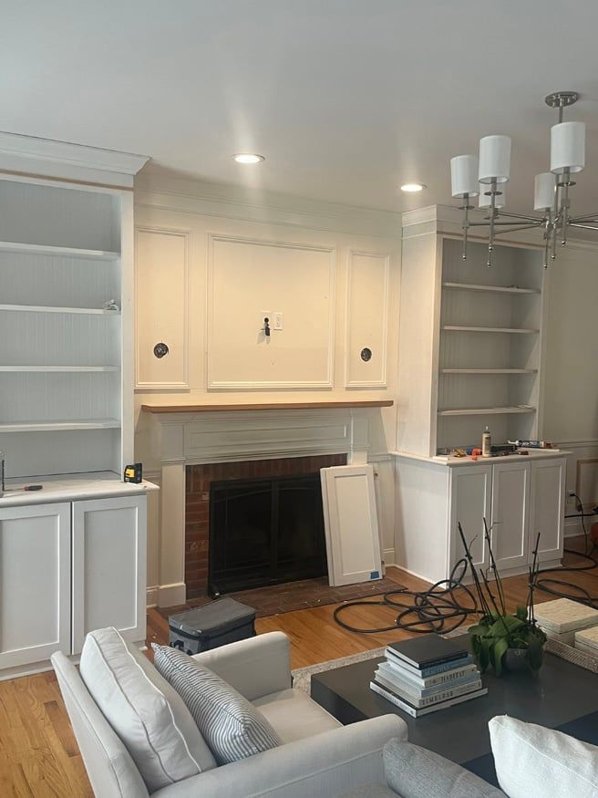 A living room with a fireplace , couch , bookshelf and chandelier.