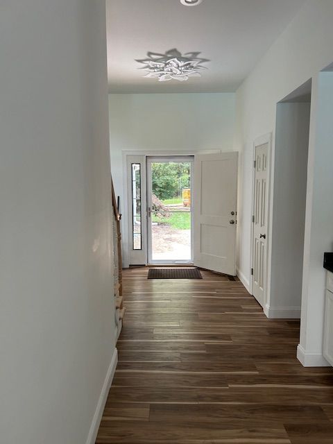A hallway with wooden floors and a door in a house.