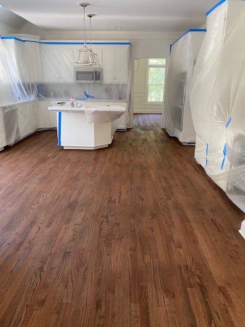 A kitchen with wooden floors and white cabinets is being painted.