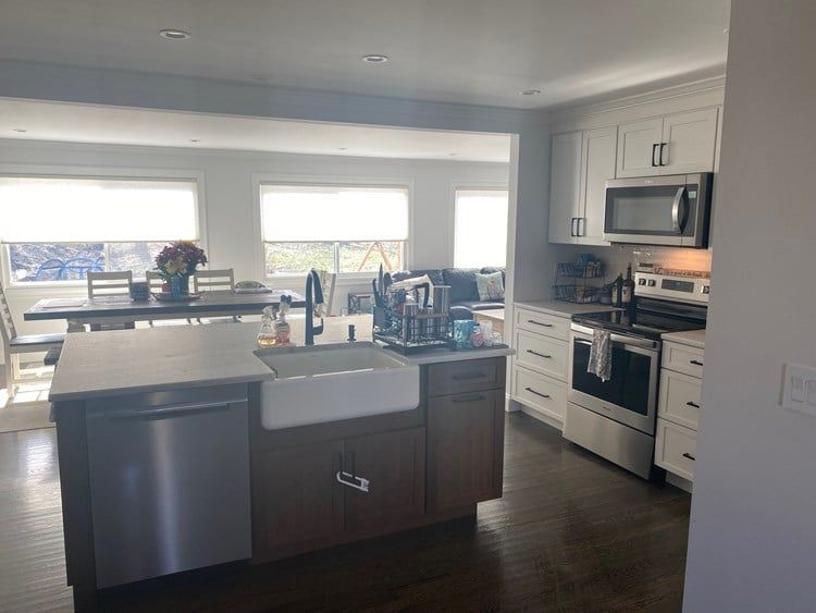 A kitchen with a sink , stove , microwave and dishwasher.