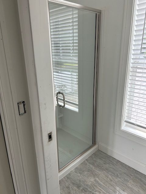 A bathroom with a walk in shower and a window.
