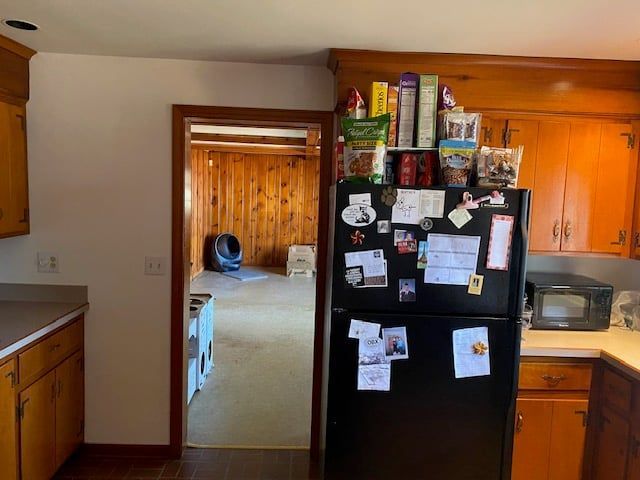 A kitchen with a black refrigerator and orange cabinets