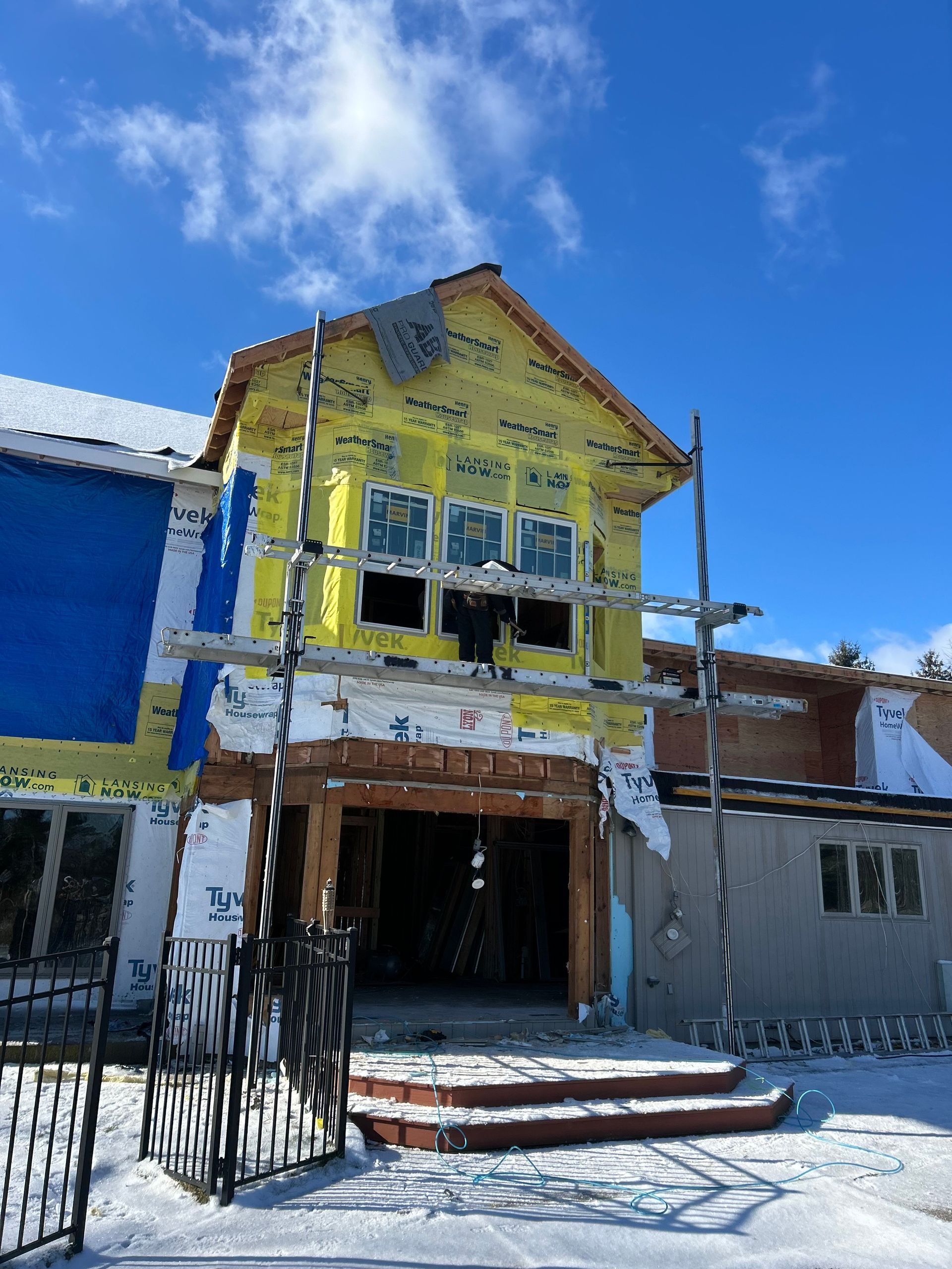 A building under construction in the snow with a blue sky in the background.