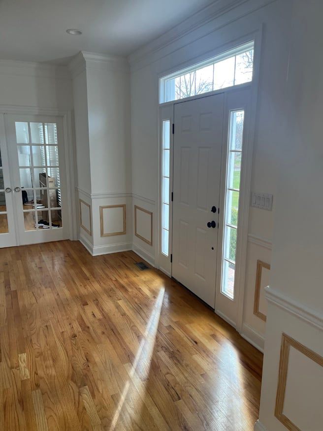 An empty room with hardwood floors and a white door.