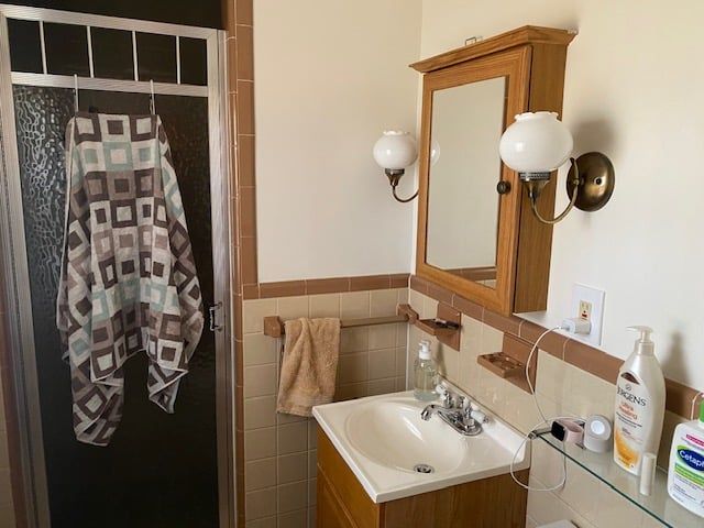 A bathroom with a sink , mirror , and shower.