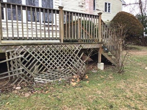 A wooden deck with a lattice railing is in the backyard of a house.