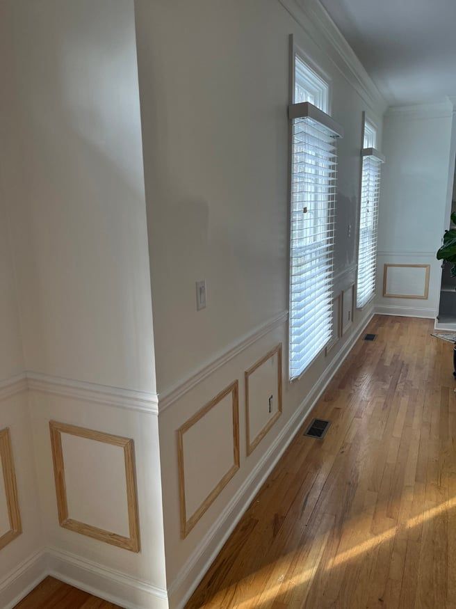 A long hallway with white walls and wooden floors in a house.