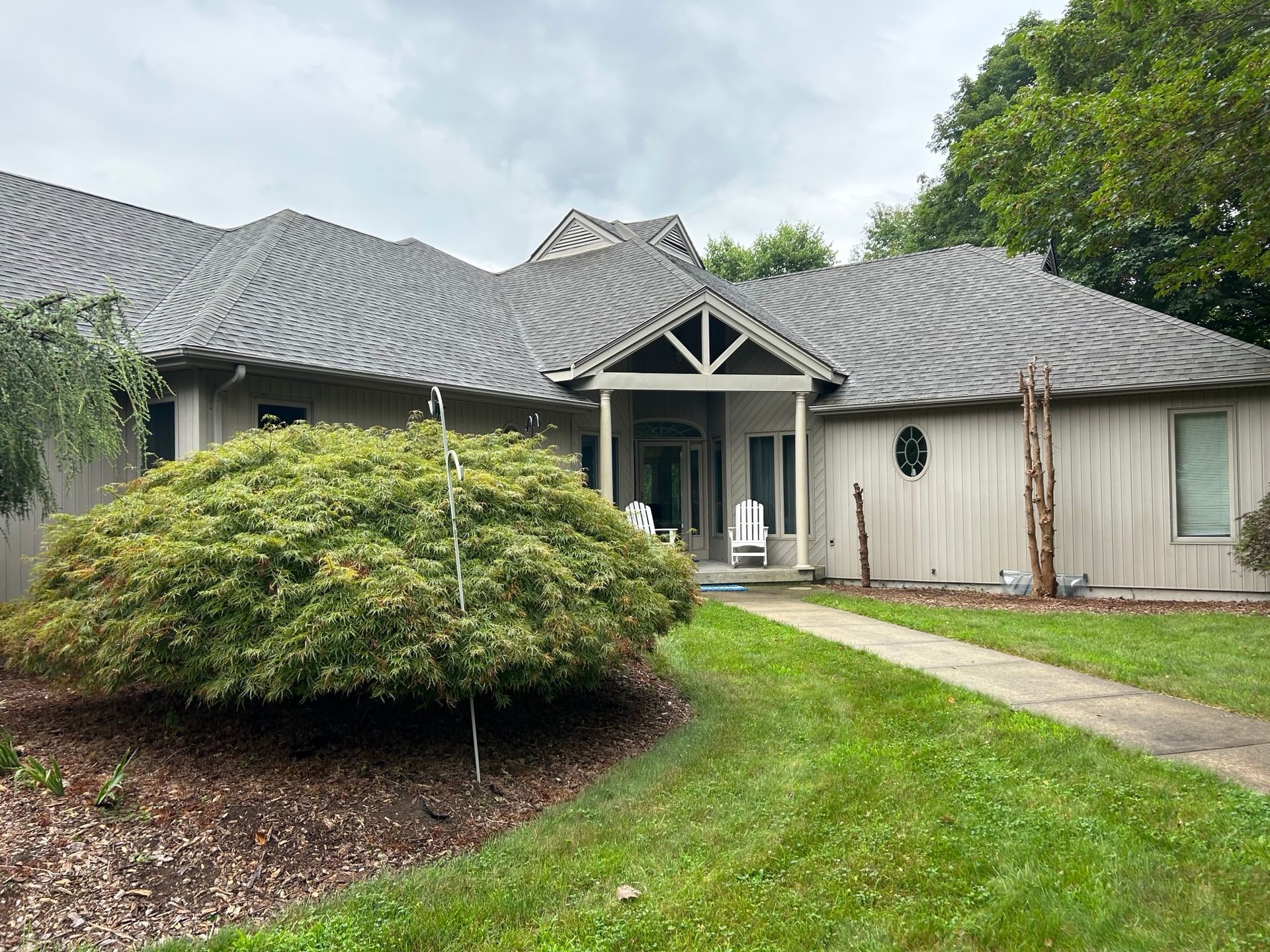 A large house with a gray roof and a porch.