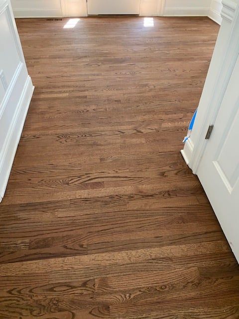 A hallway with a wooden floor and a door leading to a room.