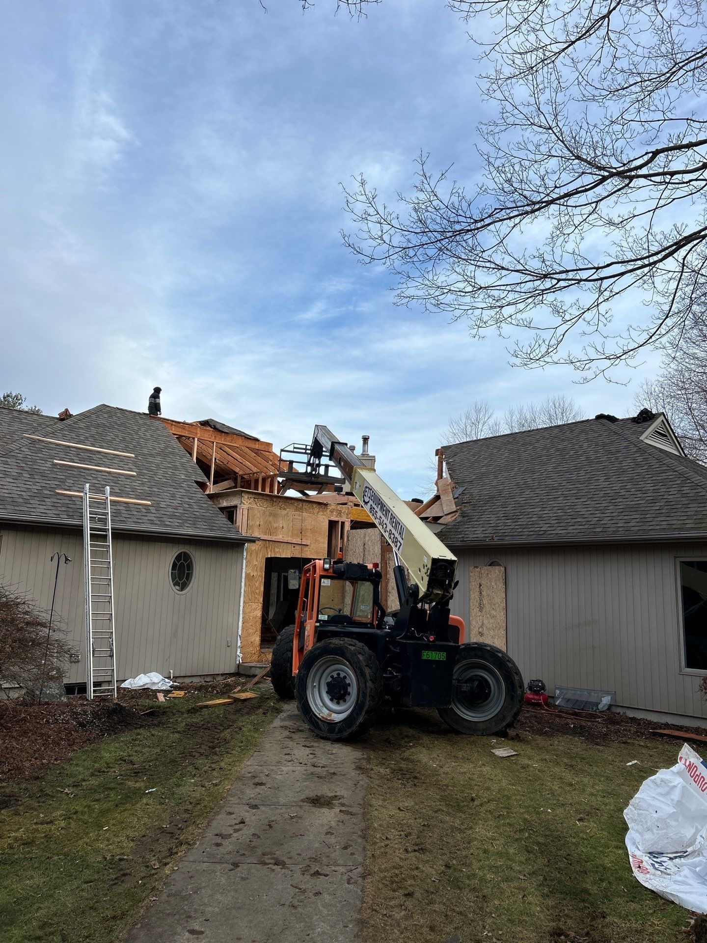 A forklift is working on the roof of a house.