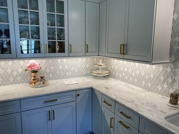 A kitchen with white cabinets and marble counter tops