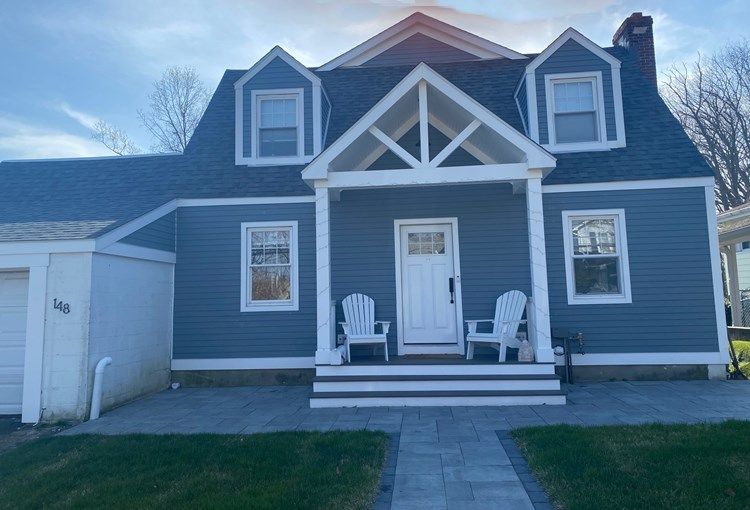 A blue and white house with a porch and chairs