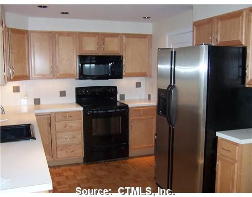 A kitchen with wooden cabinets and a stainless steel refrigerator