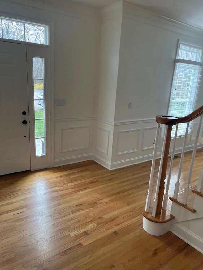 A hallway with hardwood floors and stairs in a house.