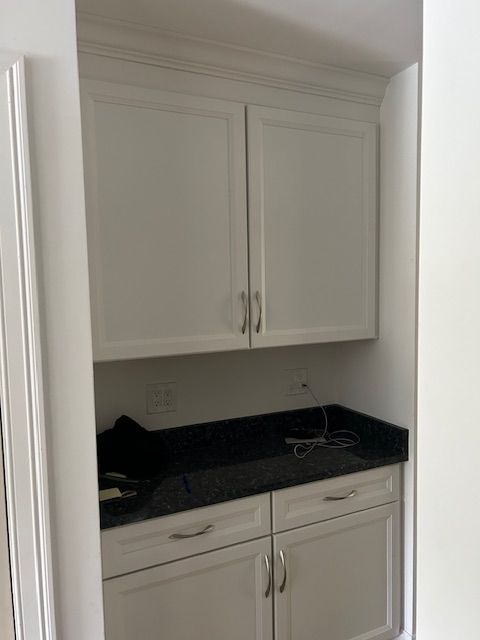 A kitchen with white cabinets and a black counter top