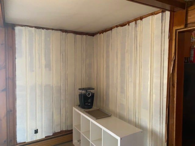A room with wood paneling and a white shelf in the corner.