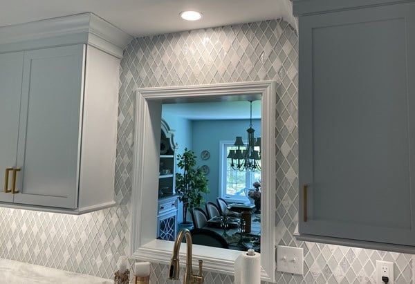 A kitchen with a sink and a window looking into the dining room.