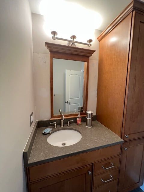 A bathroom with a sink , mirror and cabinets