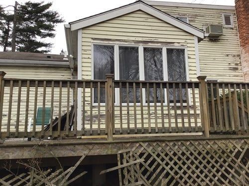 The back of a house with a wooden deck in front of it.