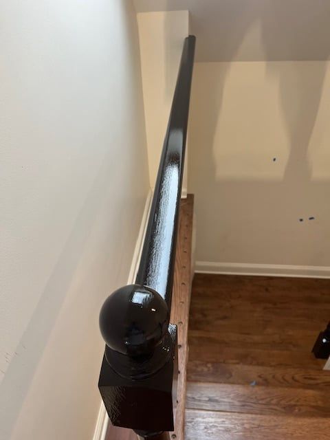 A close up of a black railing on a wooden staircase.