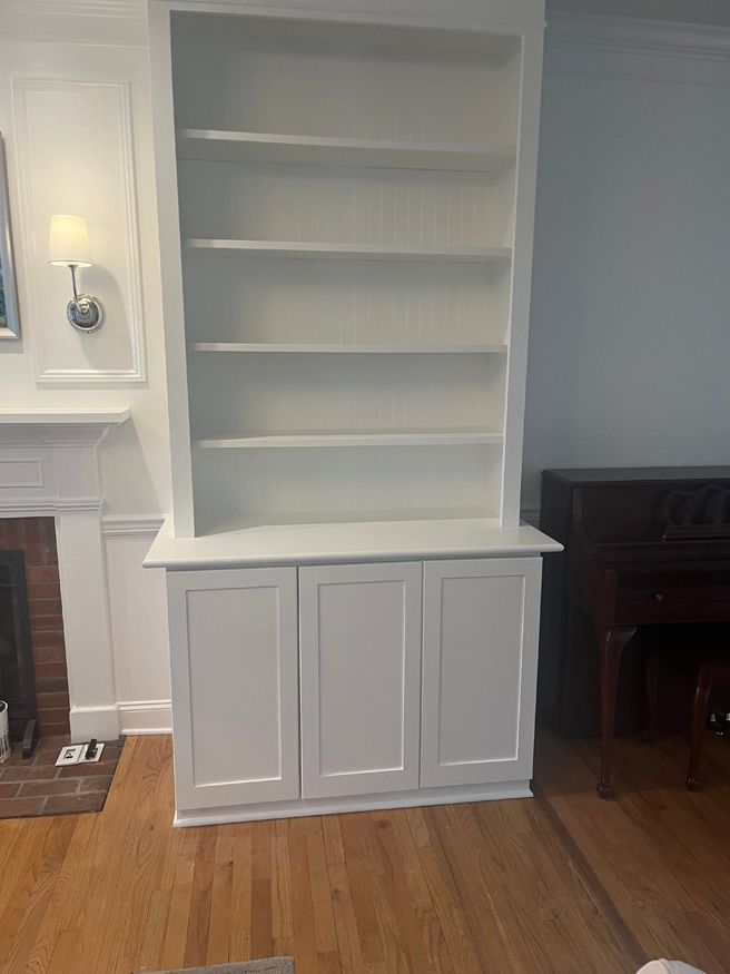A living room with a white bookshelf and a fireplace.