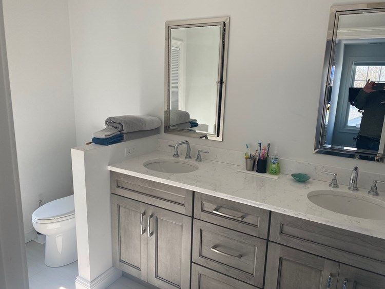 A bathroom with two sinks , a toilet and a mirror.