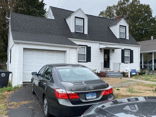 A black car is parked in front of a white house