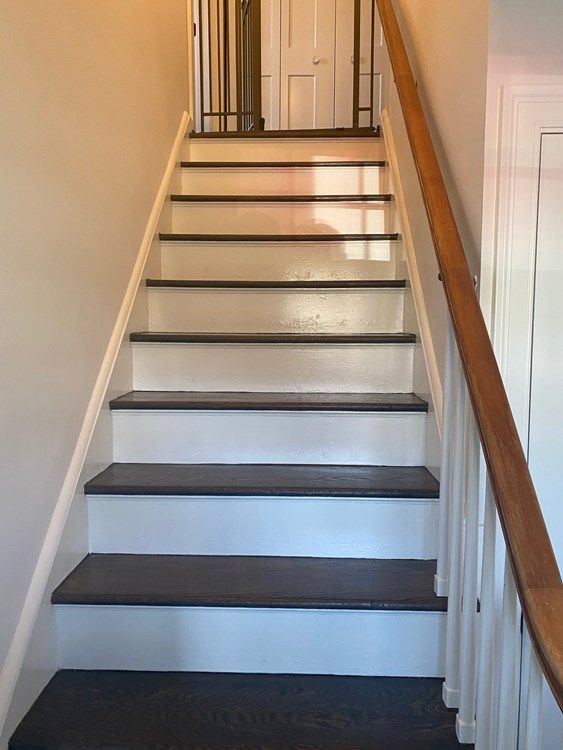 A set of white stairs with black steps and a wooden railing