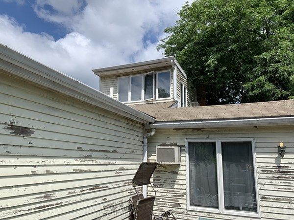 A white house with a roof that has a window on top of it.