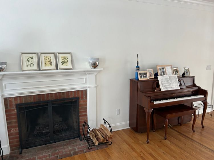 A living room with a fireplace and a piano.