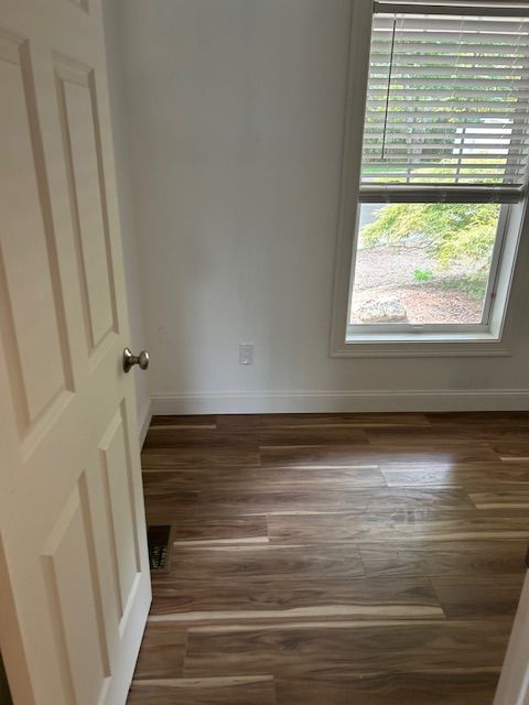 An empty room with hardwood floors and a window.
