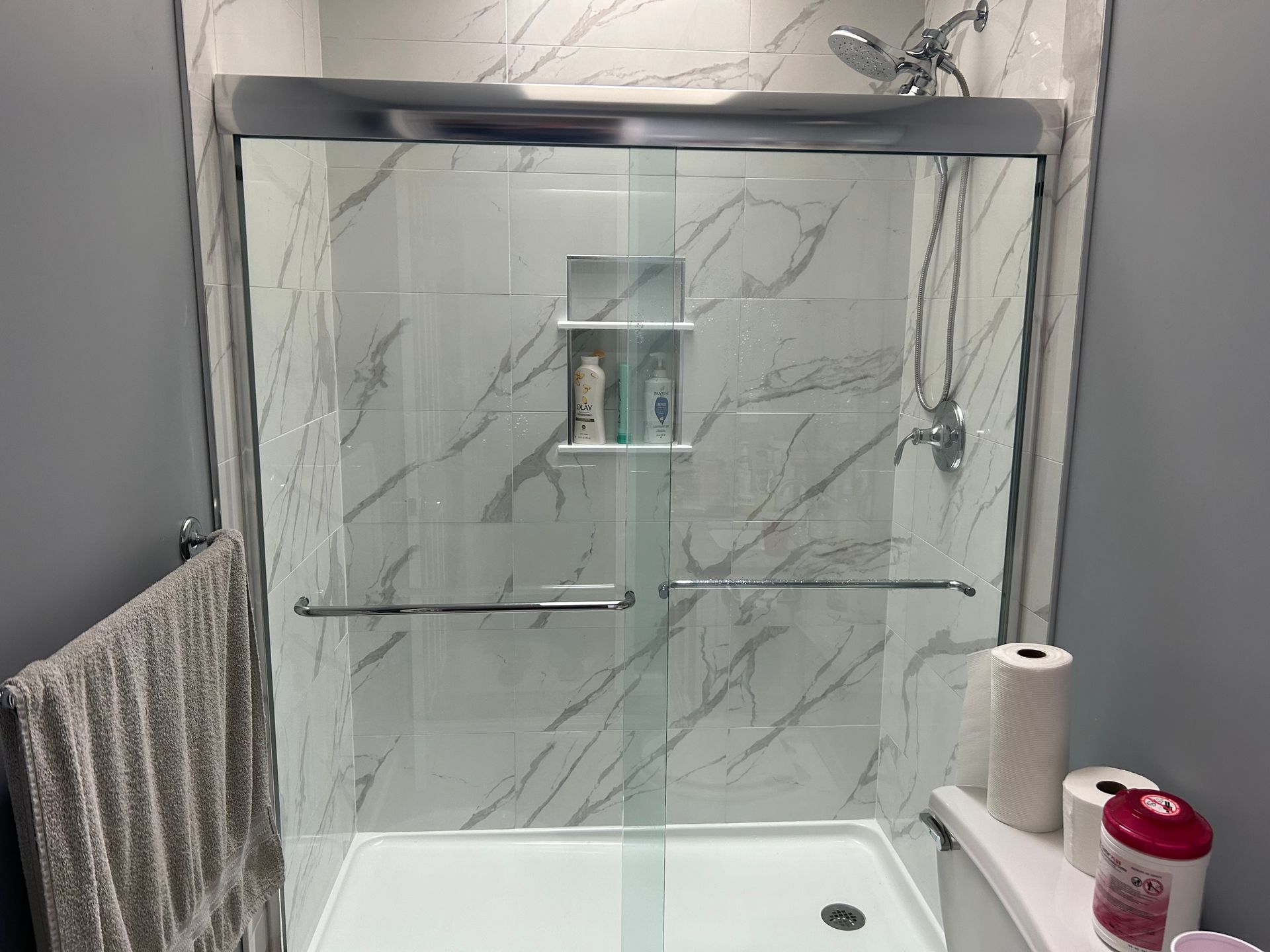 A bathroom with a sliding glass shower door and a toilet.