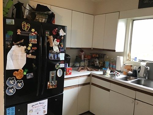 A kitchen with a black refrigerator and white cabinets.