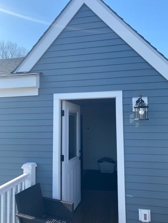 A gray house with a white trim and a white door
