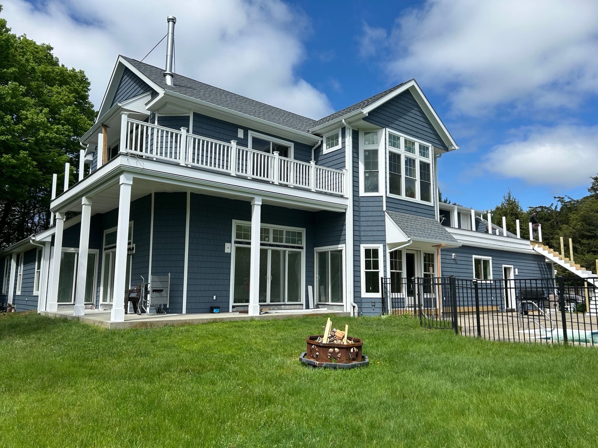 A large blue and white house with a fire pit in front of it.