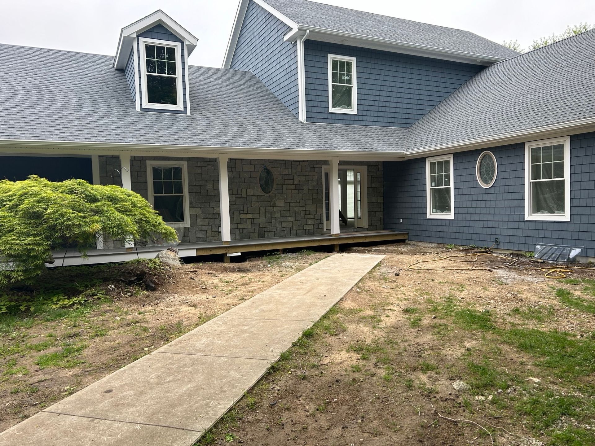 A large blue house with a porch and a walkway leading to it.