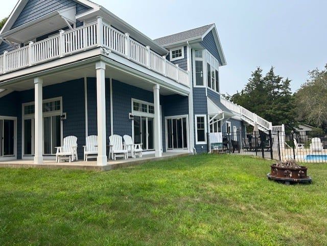 A large blue house with a white porch and a swimming pool.